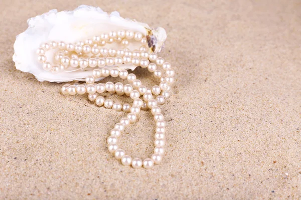 Pérolas bonitas em concha na areia, close-up — Fotografia de Stock