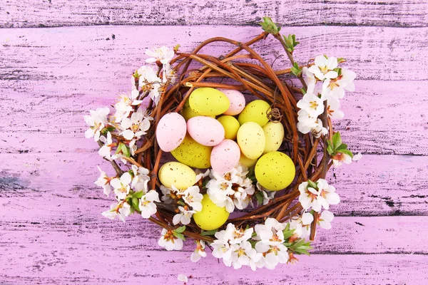 Composição com ovos de Páscoa e ramos floridos no ninho, em fundo de madeira — Fotografia de Stock