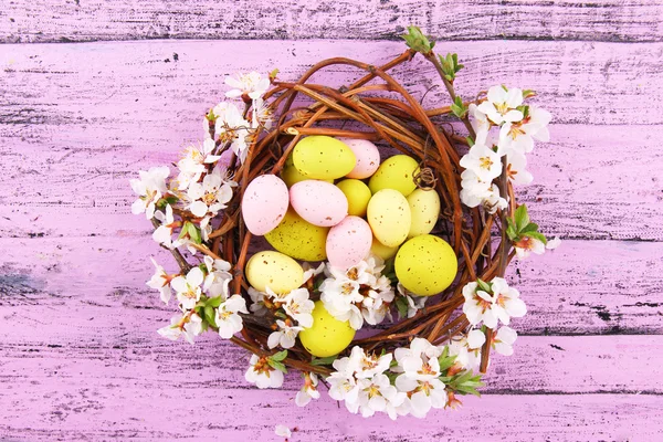 Komposition med påskägg och blommande grenar i boet, på trä bakgrund — Stockfoto