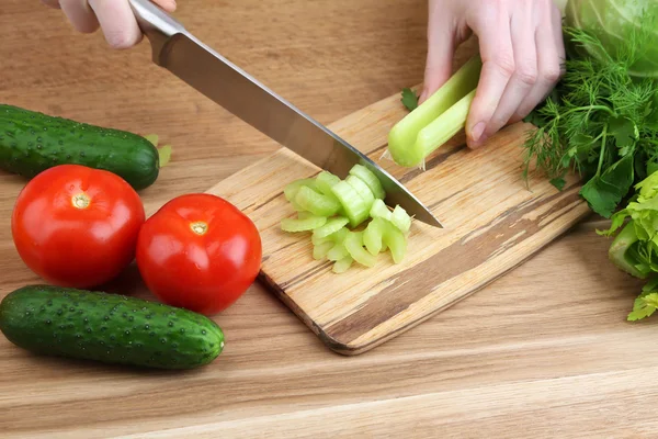 Frauenhände schneiden Sellerie auf Holzbrett, Nahaufnahme, auf Holzgrund — Stockfoto