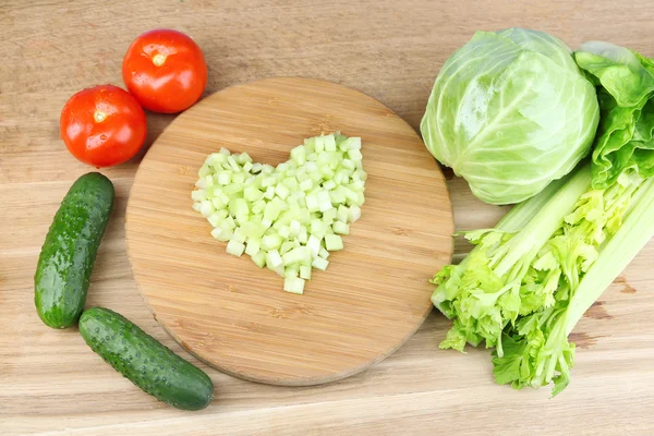 セロリのみじん切りと新鮮な野菜、木製の背景上のハート形 — ストック写真