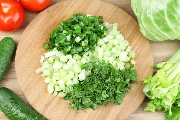 Composizione con erbe tagliate su tavola di legno e verdure fresche, su fondo di legno — Foto Stock