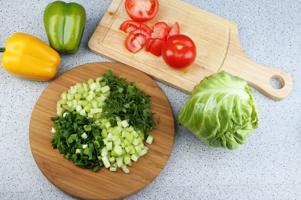 Composição com ervas picadas sobre tábua de madeira e legumes frescos, sobre fundo mesa de cozinha — Fotografia de Stock