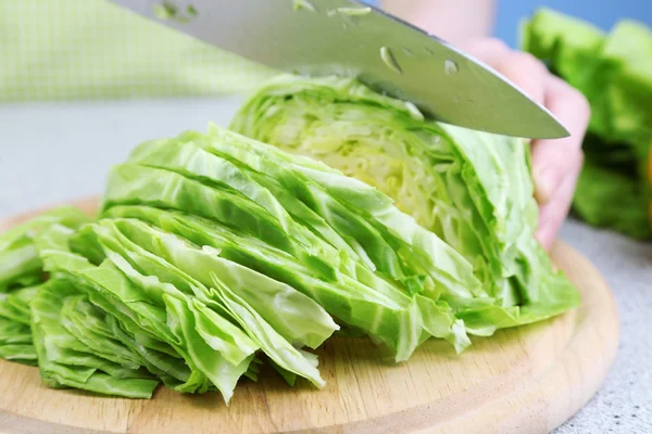 Female hands chopped cabbage on wooden board, close-up, on blue background — Stock Photo, Image