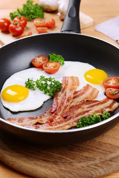 Scrambled eggs and bacon on frying pan on table close-up — Stock Photo, Image