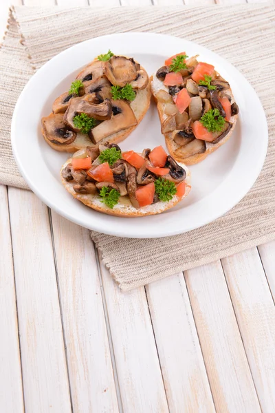 Delicious bruschetta with mushrooms on plate on table close-up — Stock Photo, Image