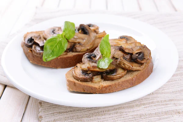 Delicious bruschetta with mushrooms on plate on table close-up — Stock Photo, Image