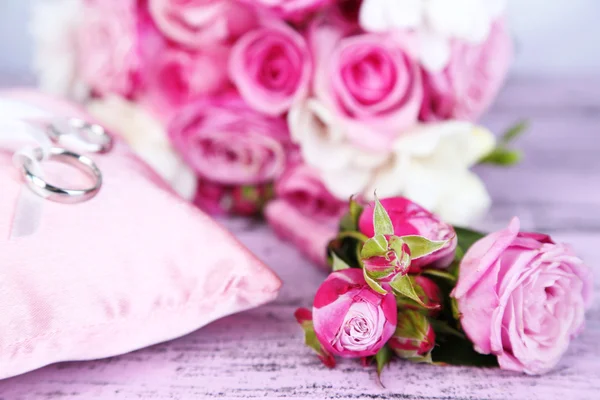 Beautiful wedding bouquet and cushion with rings on wooden background — Stock Photo, Image