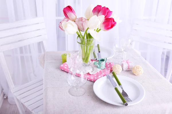 New table and chairs with table settings and spring decorations on light background — Stock Photo, Image
