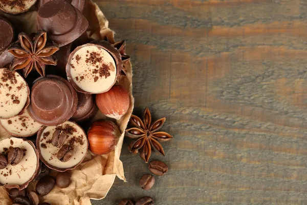 Gustose caramelle al cioccolato con chicchi di caffè e noci su sfondo di legno — Foto Stock