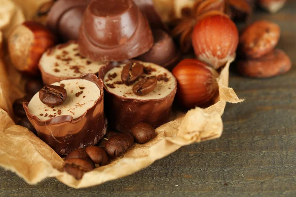 コーヒー豆と木製の背景上のナッツとおいしいチョコレート菓子 — ストック写真