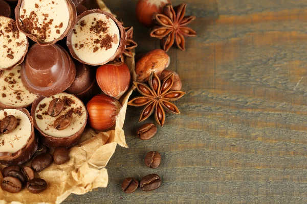 लाकडी पार्श्वभूमीवर कॉफी बीन्स आणि नट्ससह स्वादिष्ट चॉकलेट कँडीज — स्टॉक फोटो, इमेज