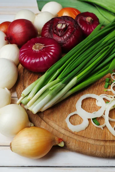 Different raw onion on wooden background — Stock Photo, Image