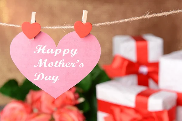 Happy Mothers Day message written on paper heart with flowers on brown background — Stock Photo, Image