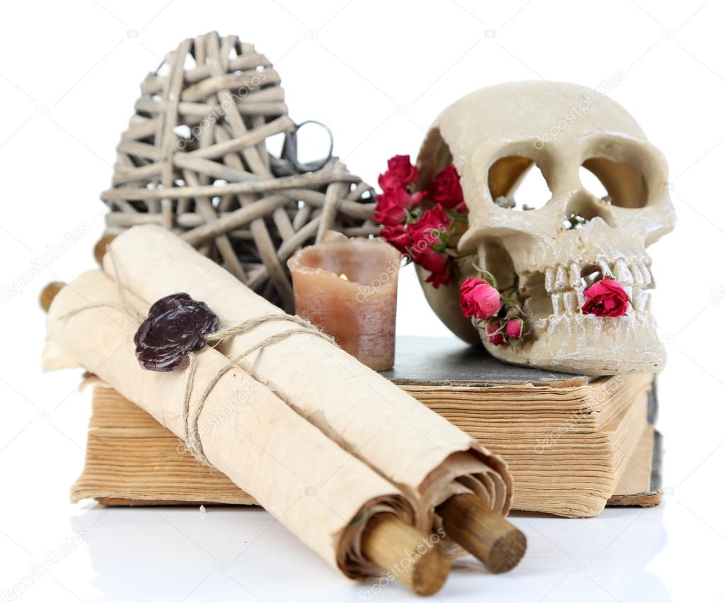 Skull, wicker heart and dried roses on old book isolated on white. Conceptual photo of love magic