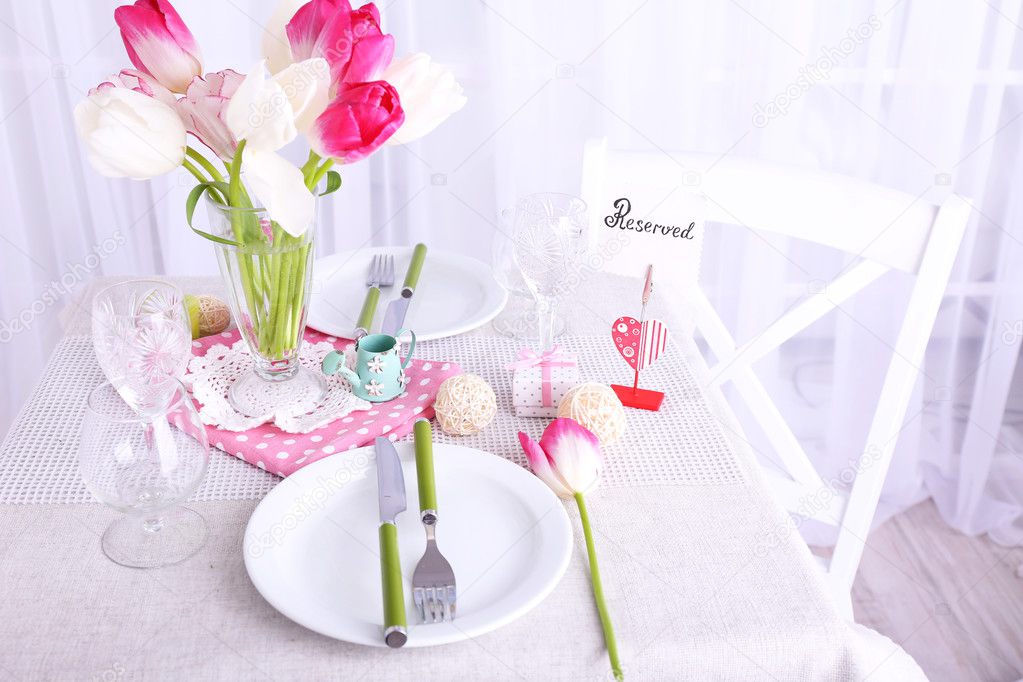 New table and chairs with table settings and spring decorations on light background