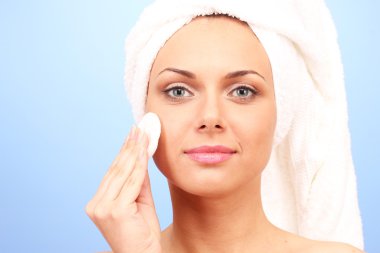 sonra duş başı ve bir pamuk yastık mavi arka plan yakın çekim üzerinde elinde bir havlu ile güzel bir genç kadın