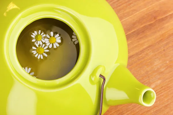 Teapot with chamomile tea on wooden table close-up — Stock Photo, Image