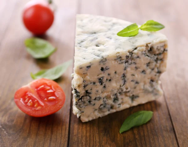 Smakelijke blauwe kaas met basilicum en tomaat, op houten tafel — Zdjęcie stockowe