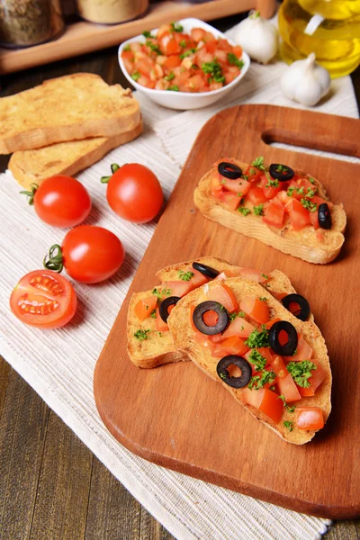 Delicious bruschetta with tomatoes on cutting board close-up — Stock Photo, Image