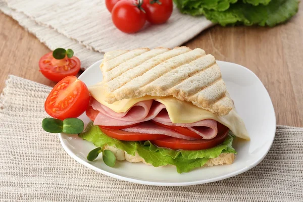 Leckeres Sandwich mit Schinken auf Holztisch — Stockfoto