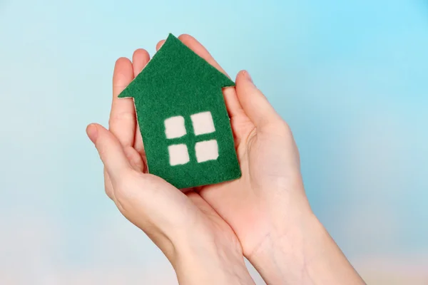 Little paper house in hand close-up, on light background — Stock Photo, Image