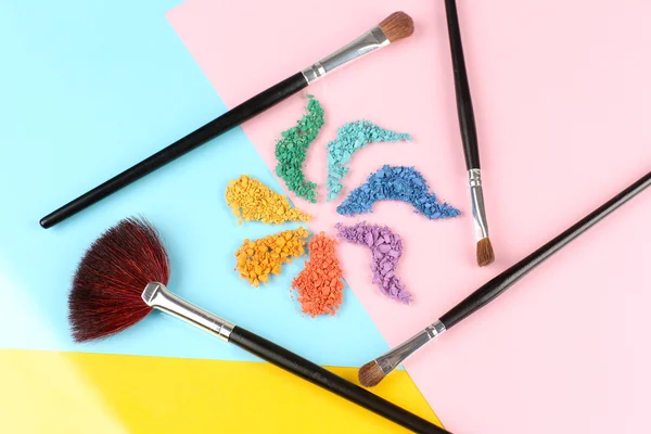 Regenboog verpletterd oogschaduw en professionele make-up borstel op kleur achtergrond — Stockfoto