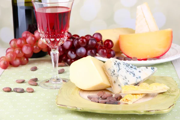 テーブルの上に並べられたチーズプレート、ブドウとワイングラス、ライトの背景 — ストック写真