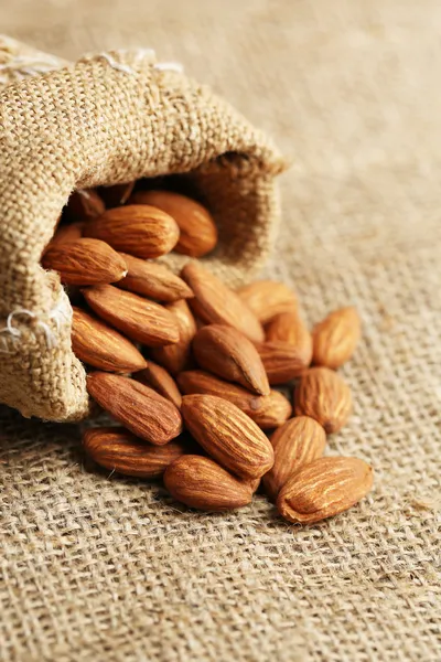 Almonds in sack on on sackcloth background — Stock Photo, Image