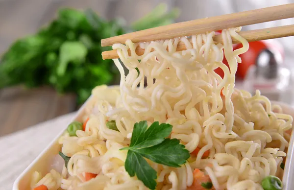 Sabrosos fideos instantáneos con verduras en un tazón en la mesa de cerca —  Fotos de Stock