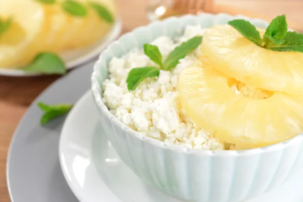 Bowl of tasty cottage cheese with pineapple on wooden table — Stock Photo, Image