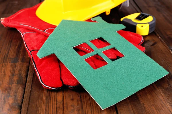 Casa de fieltro con casco y guantes sobre fondo de madera —  Fotos de Stock