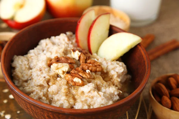 Tasty oatmeal with nuts and apples on table close up — Stock Photo, Image