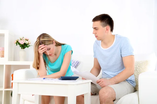 Young couple calculating finance at desk, on home interior background — Stock Photo, Image