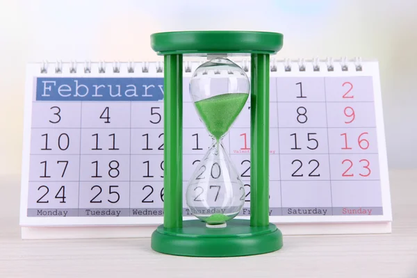 Пісочний годинник і календар на яскравому фоні — стокове фото
