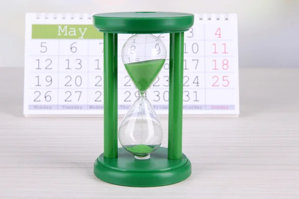 Hourglass and calendar on bright background — Stock Photo, Image