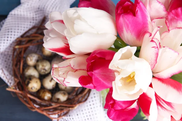 Složení s velikonoční vajíčka a krásné tulipány ve skleněné konvici na barevné dřevěné pozadí — Stock fotografie