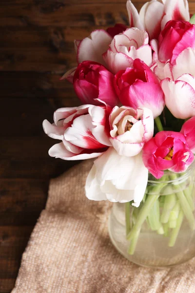 Piękne tulipany w dzbanku szkła na drewniane tła — Zdjęcie stockowe