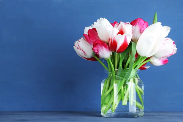 Belles tulipes dans une cruche en verre sur fond en bois couleur — Photo