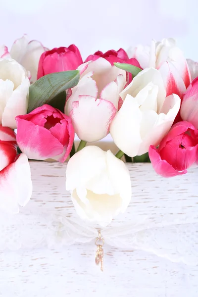 Hermosos tulipanes en caja de madera, sobre fondo claro — Foto de Stock