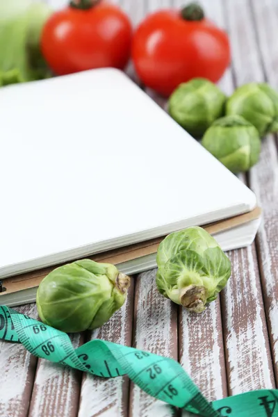 Notebook z pomiaru taśmę i warzywa na drewniane tła — Zdjęcie stockowe