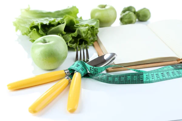 Talheres amarrados com fita métrica e livro com verduras isoladas em branco — Fotografia de Stock