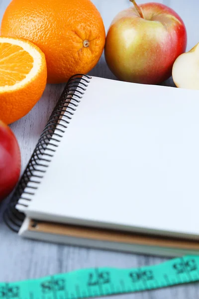 Notebook z pomiaru taśmę i owoce na drewniane tła — Zdjęcie stockowe