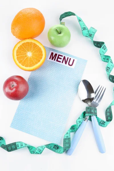 Talheres amarrados com fita métrica e menu com frutas isoladas em branco — Fotografia de Stock