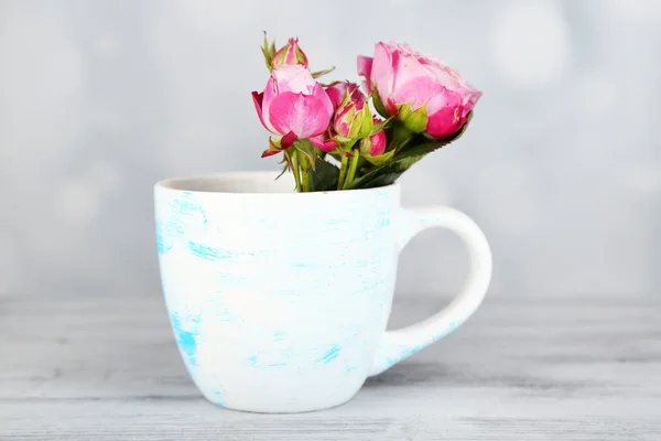 Schöne Rosen in Tasse auf hellem Hintergrund — Stockfoto