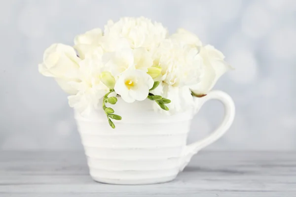 Bellissimi fiori primaverili in tazza su sfondo chiaro — Foto Stock