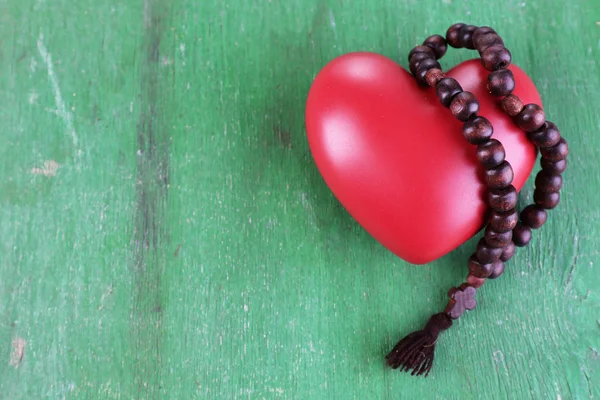 Heart with rosary beads on wooden background — Stock Photo, Image