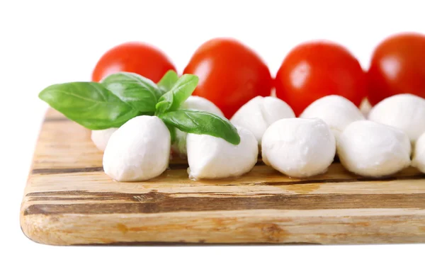Smakelijke mozzarella kaas ballen met basilicum en rode tomaten, op snijplank, geïsoleerd op wit — Stockfoto