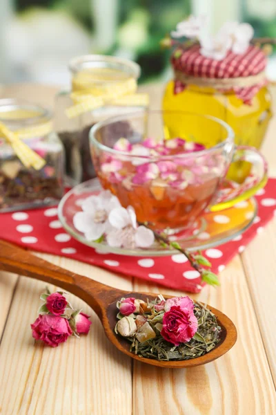 Assortment of herbs, honey and tea in glass jars on wooden table, on bright background — Stock Photo, Image