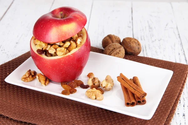 Manzana rellena con nueces y canela en plato sobre fondo de madera —  Fotos de Stock